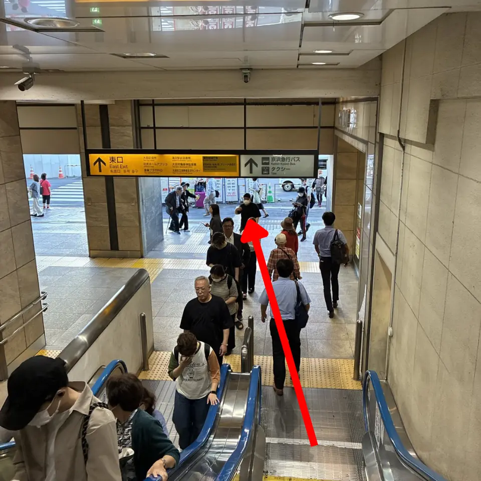 JR蒲田駅東口方面のエスカレーターを降りて駅の外へ出る様子（矢印は進行方向）